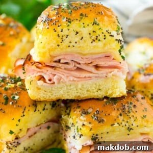 Savory ham and cheese sliders arranged on a serving plate, beautifully garnished with fresh parsley.