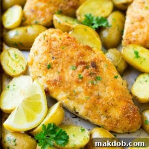 Delicious Italian chicken with a golden parmesan crust, served alongside perfectly roasted potatoes and fresh parsley.