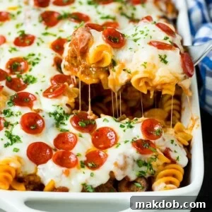 A spoon dishing out a generous portion of delicious pizza casserole, brimming with cheesy goodness.