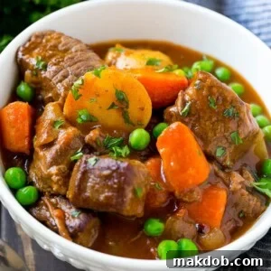 A comforting bowl of slow cooker beef stew, brimming with tender meat, sweet carrots, wholesome potatoes, and green peas.