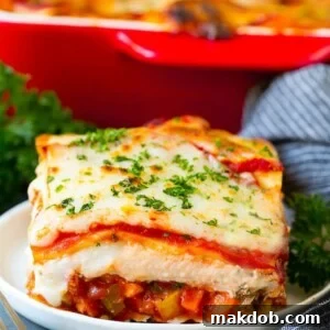 A generous slice of vegetable lasagna, beautifully topped with melted cheese and fresh parsley.