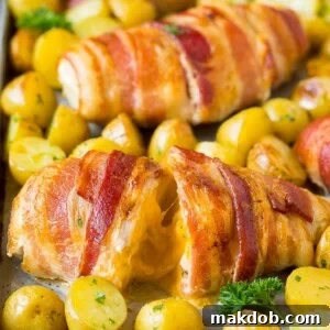Perfectly cooked bacon wrapped stuffed chicken breast on a sheet pan, served alongside tender roasted potatoes for a complete meal.