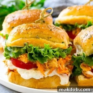 A delectable plate of buffalo chicken sliders, layered with fresh lettuce, juicy tomato, and creamy ranch dressing.