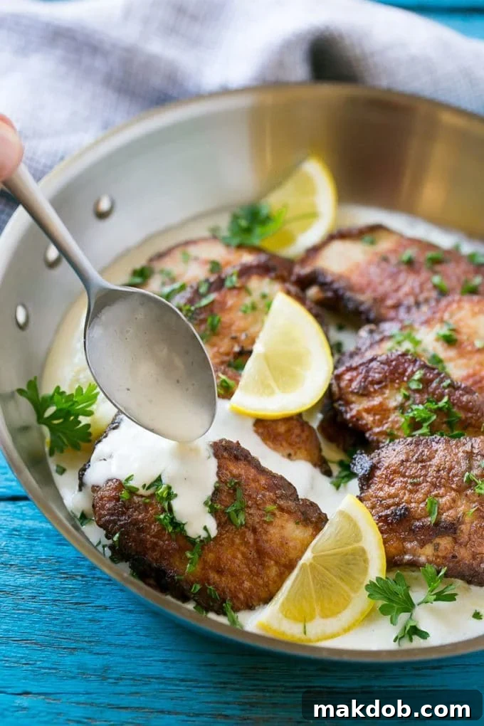 Pork Scallopini with Creamy Lemon Sauce - An Easy 30-Minute Dinner Pork scallopini in a pan with a spoon drizzling creamy sauce over the top.