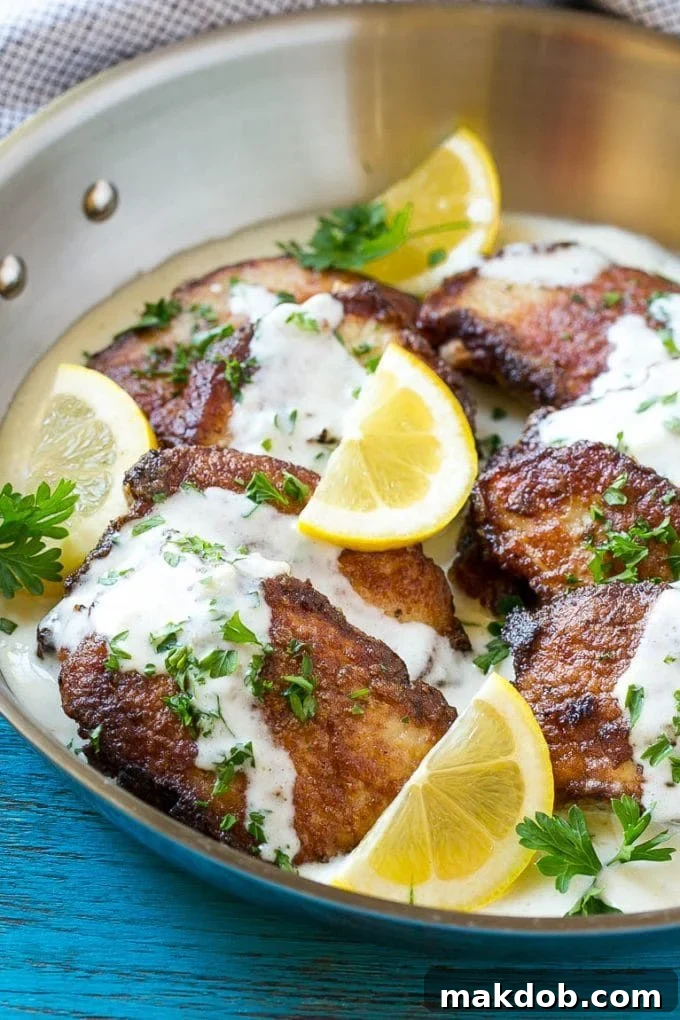 Delicious Pan-Seared Pork Scallopini with Lemon Cream Sauce Pork loin sliced, breaded, and coated in a creamy sauce, ready to serve.