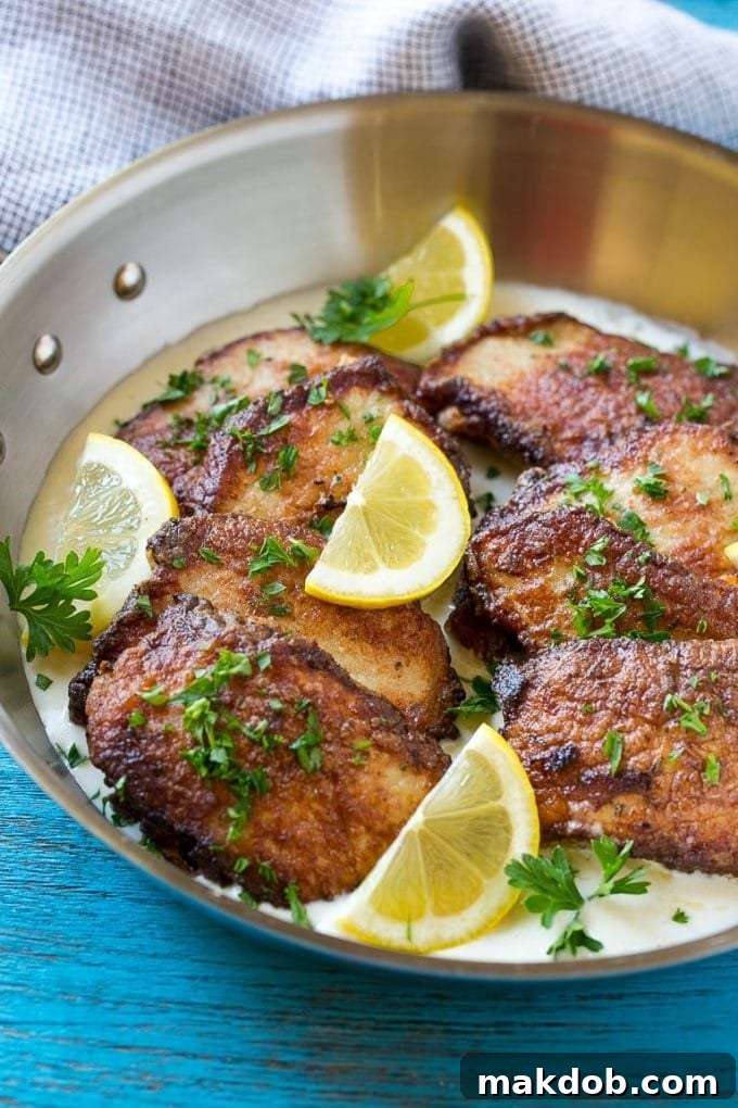 Pork Scallopini with Creamy Lemon Sauce - Ready to Serve Slices of pork scallopini in a bed of creamy lemon sauce, garnished with fresh lemon and parsley.