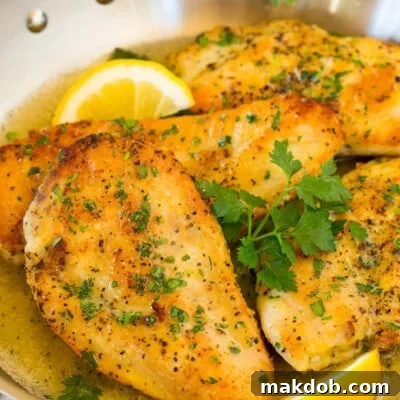 A pan of lemon pepper chicken garnished with parsley and lemons.