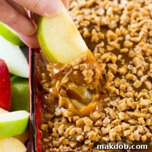 A hand expertly scooping out a serving of luscious caramel apple dip, demonstrating its rich, creamy texture and inviting appeal.