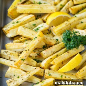 A sheet pan filled with beautifully roasted parsnips, golden brown and tender, garnished with a sprinkle of fresh green parsley, ready to be served as a delightful side.