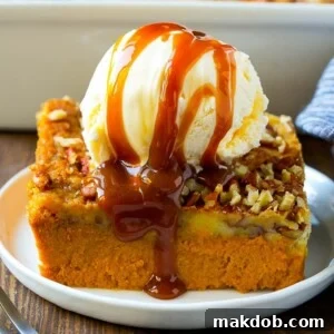 A generous slice of pumpkin dump cake, decadently topped with a scoop of vanilla ice cream and a drizzle of rich caramel sauce, promising a delightful treat.