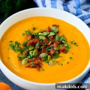 A comforting bowl of rich pumpkin soup, elegantly topped with crispy bacon bits and crunchy pumpkin seeds, ready to be savored.