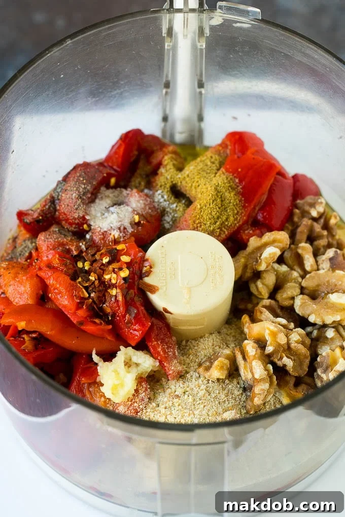 Fresh ingredients for Muhammara, including vibrant roasted red bell peppers, golden toasted walnuts, olive oil, a bowl of spices, and breadcrumbs, artfully arranged on a wooden board before blending.