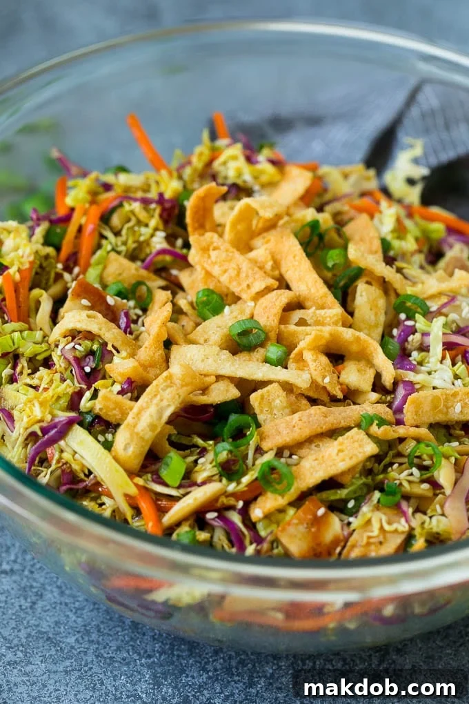 A vibrant platter of Chinese chicken salad showcasing a colorful mix of cabbage, carrots, and an abundance of crispy wonton strips, inviting you to take a bite.