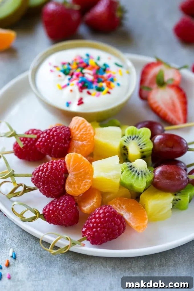 Colorful fruit kabobs artfully arranged and served with a creamy yogurt dipping sauce, perfect for a healthy snack or party appetizer.