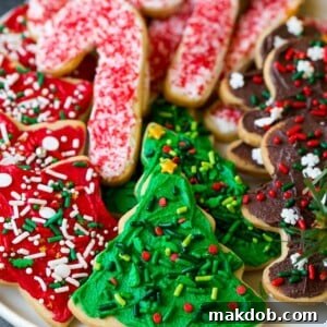 A serving plate of classic Christmas sugar cookies, beautifully decorated with vanilla buttercream frosting and festive sprinkles.