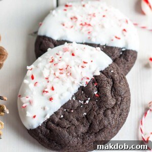 An image of two dark chocolate candy cane cookies, showcasing the festive peppermint swirl.