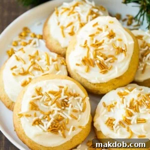 Eggnog cookies, elegantly topped with frosting and a dusting of gold sprinkles, arranged on a festive serving plate.