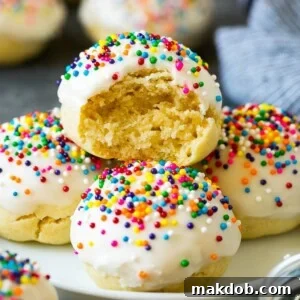 A plate of soft Italian cookies, with a tempting bite taken out of one, revealing its delicate texture.