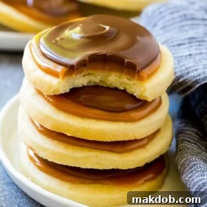 A stack of delicious Twix cookies with a satisfying bite taken out of one, revealing the layers.