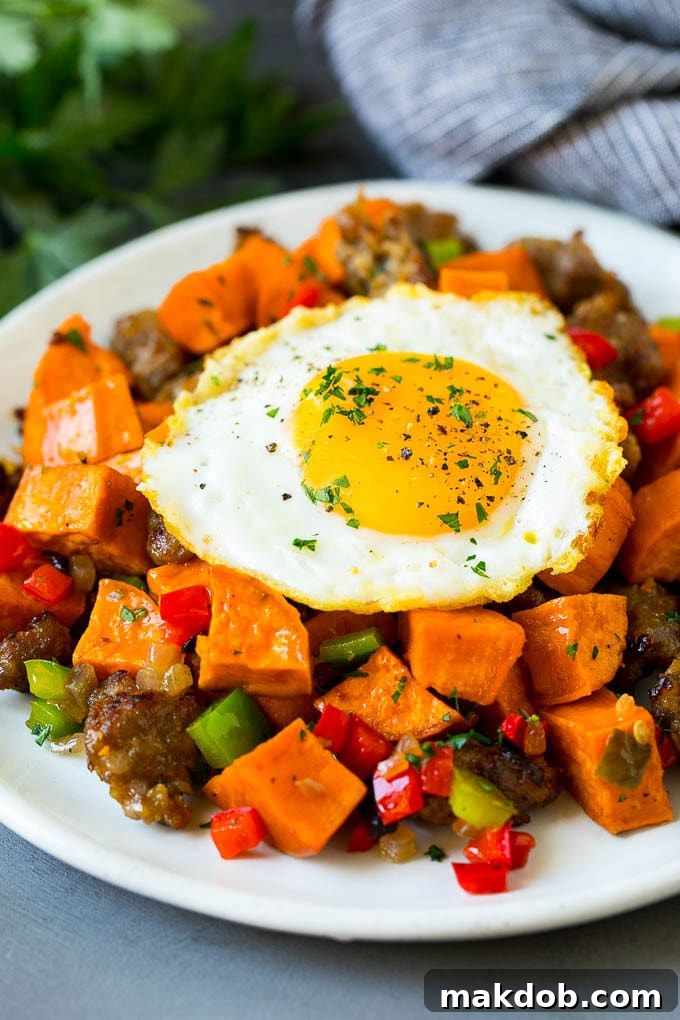 Sweet potato hash with sausage, topped with a fried egg. A close-up shot of the colorful and inviting dish.