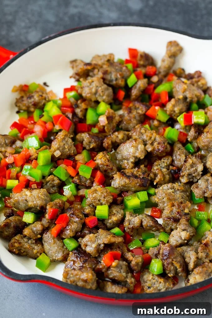 Sausage, onions and bell peppers simmering together in a skillet, creating a vibrant mix.