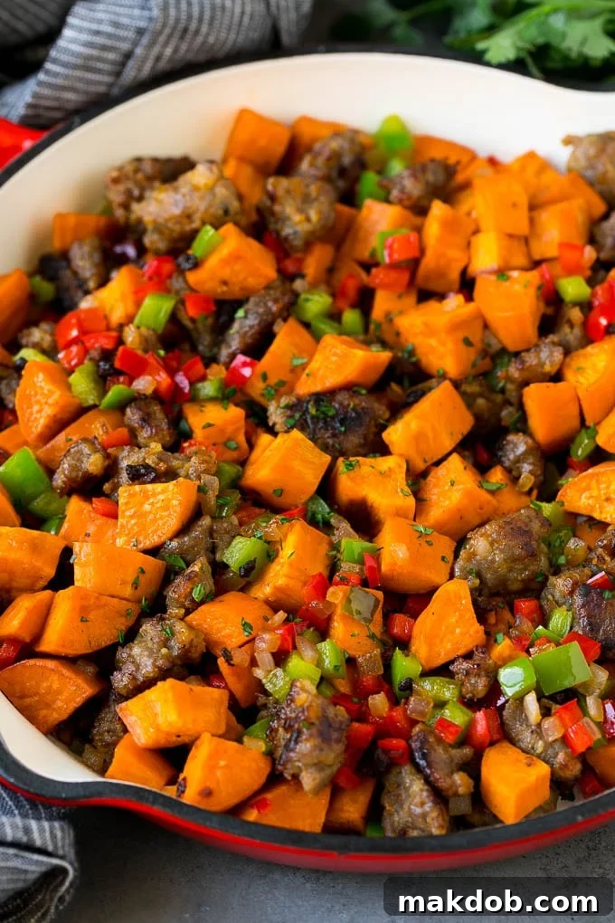 A colorful and hearty hash with sweet potatoes, sausage, and various vegetables in a pan.
