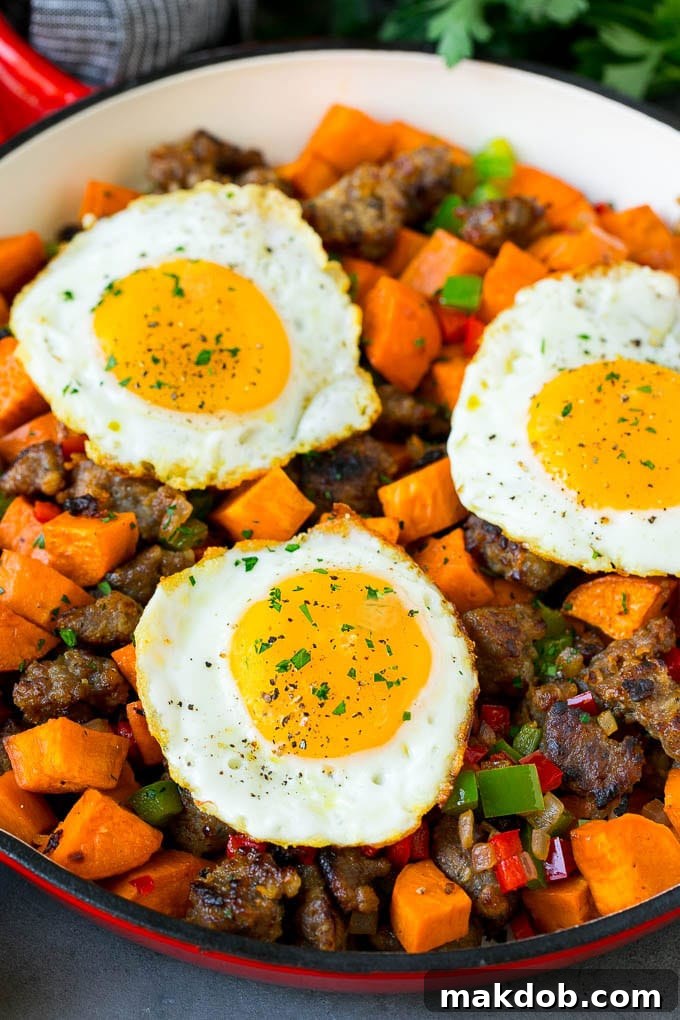 A pan of sweet potato hash topped with two perfectly fried eggs, garnished with parsley.