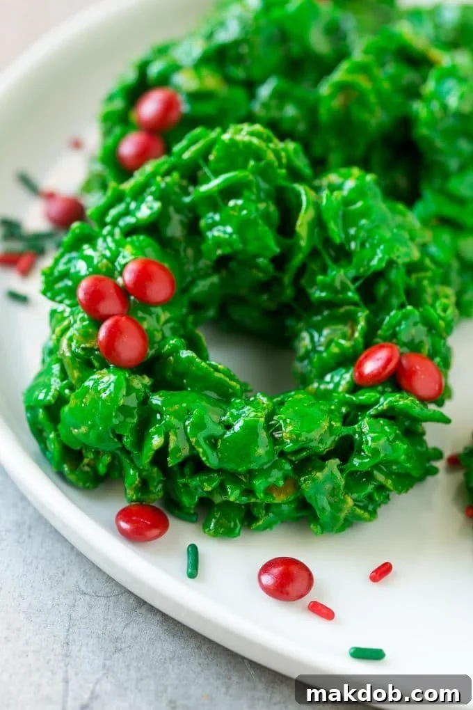 Christmas Wreath Cookies Recipe | Cornflake Wreaths | Cornflake Cookies | No Bake Cookie Recipe #cookies #wreath #christmas #holiday #nobake #dessert #dinneratthezoo A vibrant display of red and green no-bake Christmas wreath cookies, showcasing their festive appeal on a white plate.