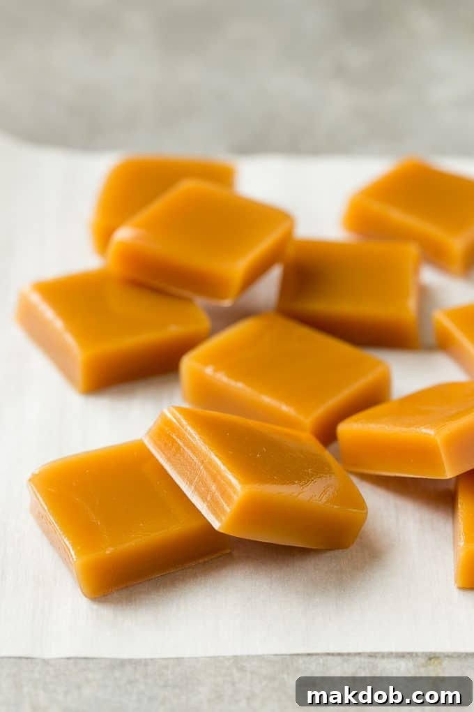 Perfectly cut squares of golden microwave caramel arranged neatly on parchment paper, showcasing their smooth, inviting texture.