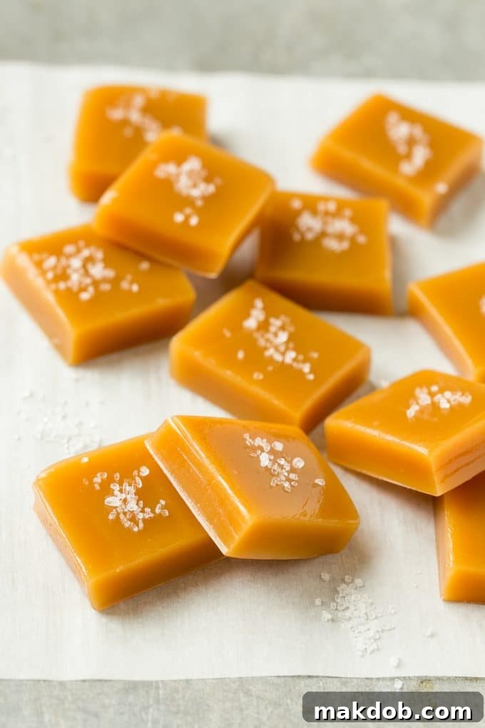 Individual squares of golden homemade caramel, generously topped with coarse sea salt, ready to be enjoyed as a sweet and savory treat.