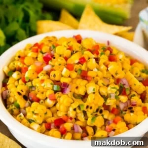 A bowl of corn salsa surrounded by tortilla chips.