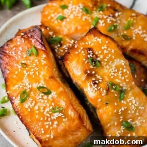 A platter of miso salmon fillets topped with sesame seeds and green onions.