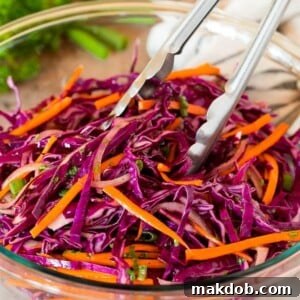 Tongs serving up a portion of red cabbage slaw.