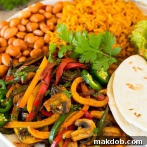A platter of vegetarian fajitas served with rice and beans.