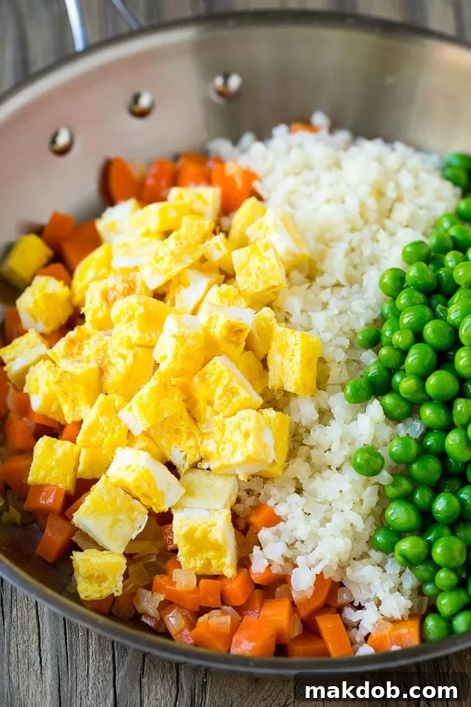 Guilt-Free Cauliflower Fried Rice 4 Cooked carrots, onions, scrambled eggs, peas, and riced cauliflower stir-fried together in a large pan.