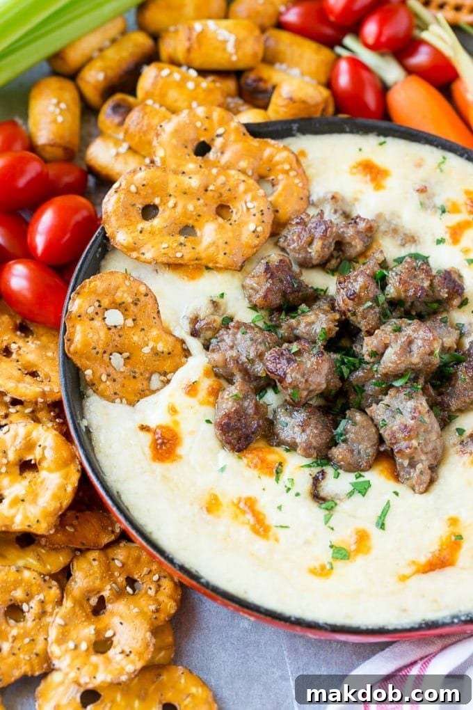 Brat & Beer Cheese Dip Recipe | Beer Cheese Dip | Cheese Dip | Easy Appetizer #beer #cheese #dip #sausage #appetizer #dinneratthezoo Beer cheese dip with pretzel chips scooping into it.