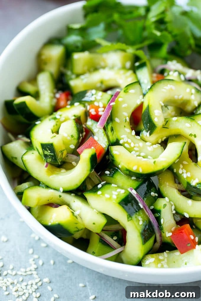 A beautifully presented bowl of Asian cucumber salad, adorned with dressing and a generous sprinkle of sesame seeds, ready to be enjoyed.