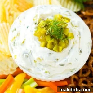 A bowl of creamy dill pickle dip served with a variety of fresh vegetables, offering a unique tangy flavor.