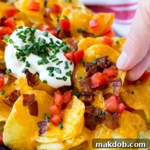 Irish nachos loaded with cheese, bacon, sour cream, tomatoes, and chives, a hearty twist on a classic.