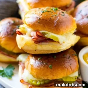A pile of savory Cuban sliders filled with ham, cheese, and pickles, brushed with garlic butter.