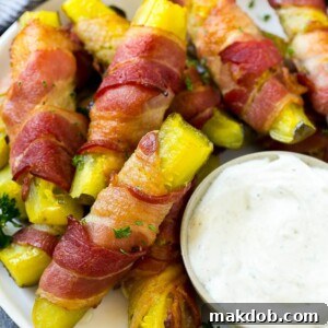 Bacon wrapped pickles on a plate with a side of ranch dressing.