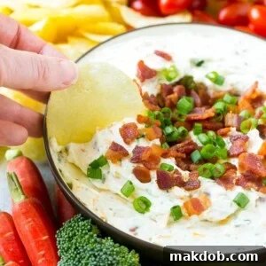 A bowl of creamy dip topped with crispy bacon and vibrant green onions, ready to serve.