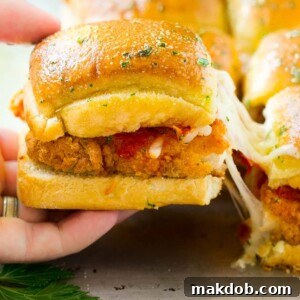 A crispy chicken sandwich being pulled away by a hand.