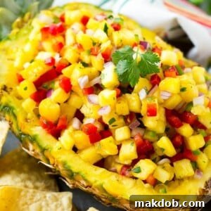 A pineapple boat filled with vibrant pineapple salsa, ready to serve with tortilla chips.