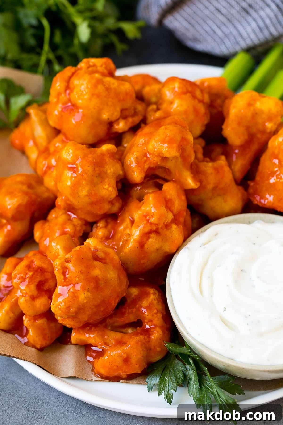 Buffalo cauliflower bites served with ranch and celery, arranged beautifully on a plate.