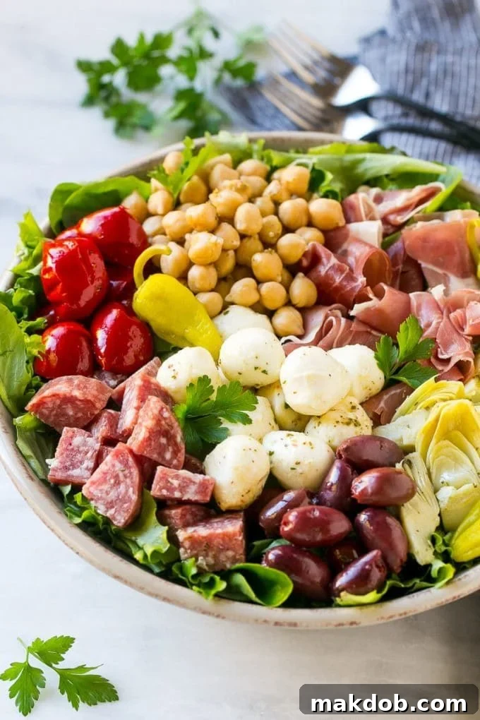 Antipasto Salad Recipe | Italian Salad | Main Course Salad | Antipasto Recipe #salad #salami #italianfood #dinner #lunch #dinneratthezoo Close-up of Antipasto salad with cured meats, fresh mozzarella cheese, roasted red peppers, and olives elegantly arranged over a bed of crisp salad greens, showcasing the rich variety of ingredients.