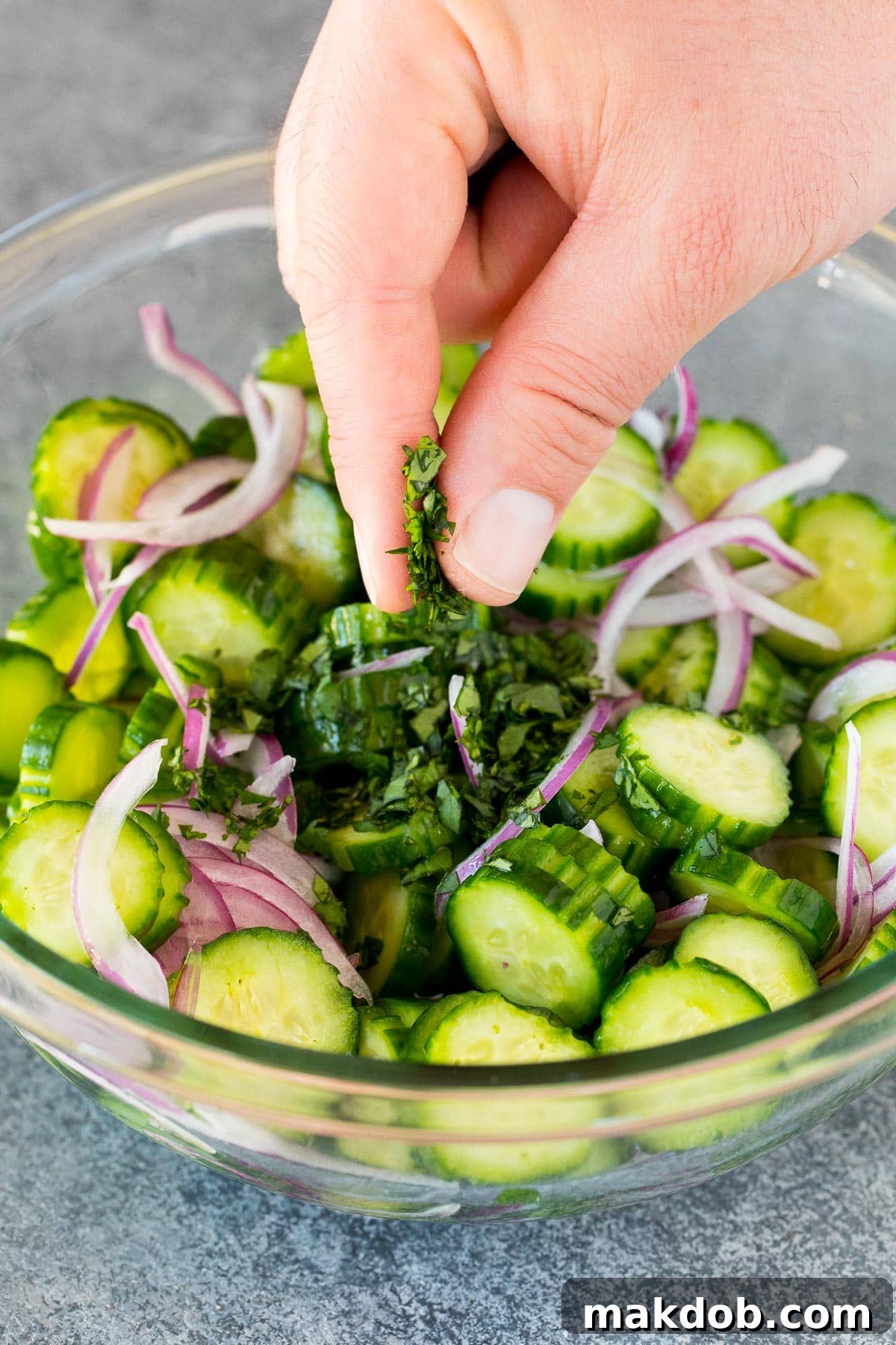 Fresh cilantro being sprinkled over a bowl of Thai cucumber salad, adding a burst of color and aroma.