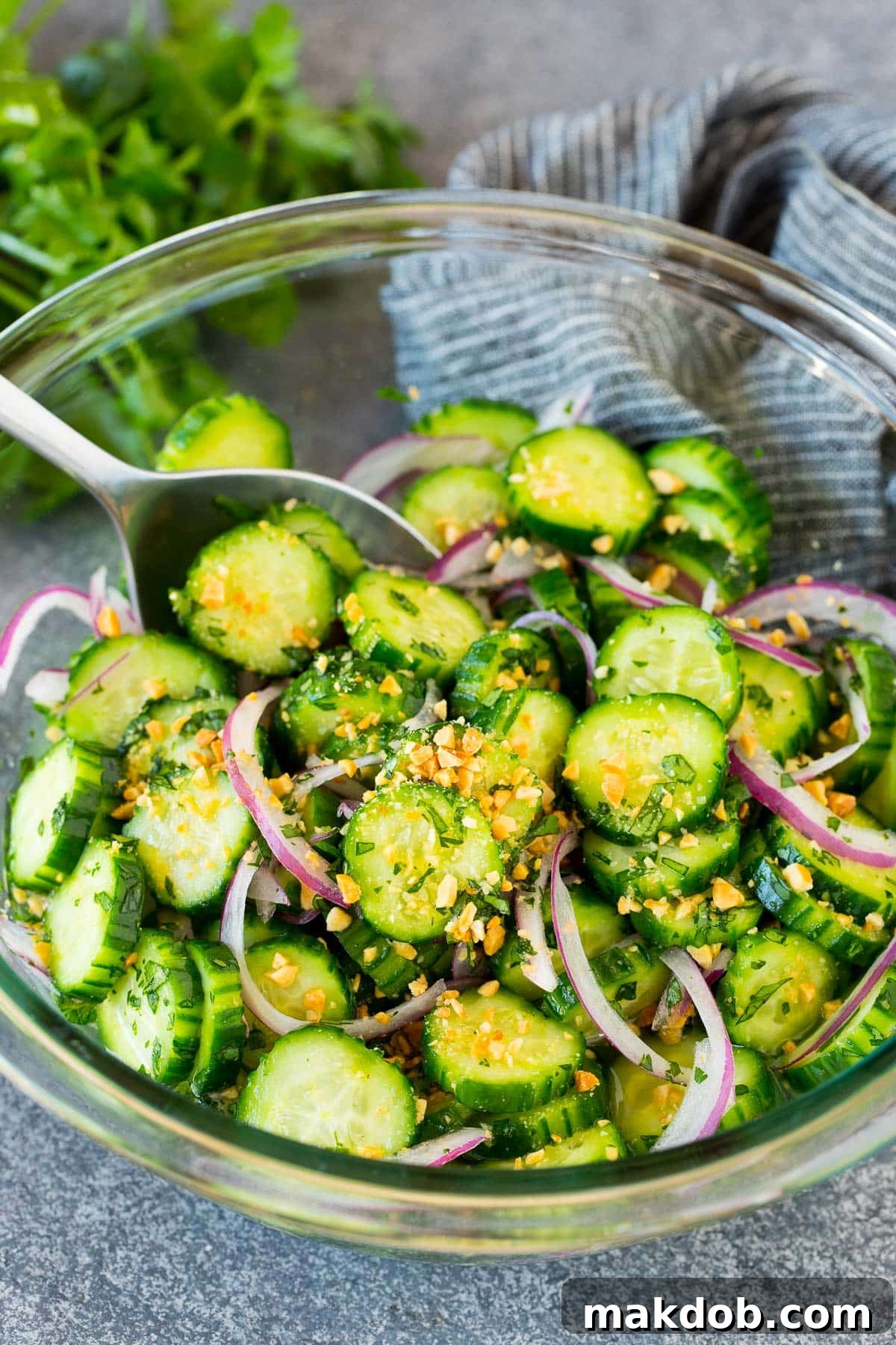Thai cucumber salad in a bowl with a serving spoon.