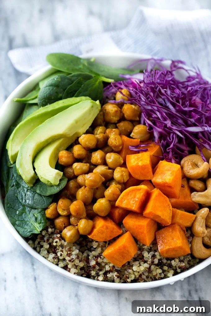 Sweet potatoes, chickpeas, avocado and quinoa arranged over purple cabbage in a bowl.