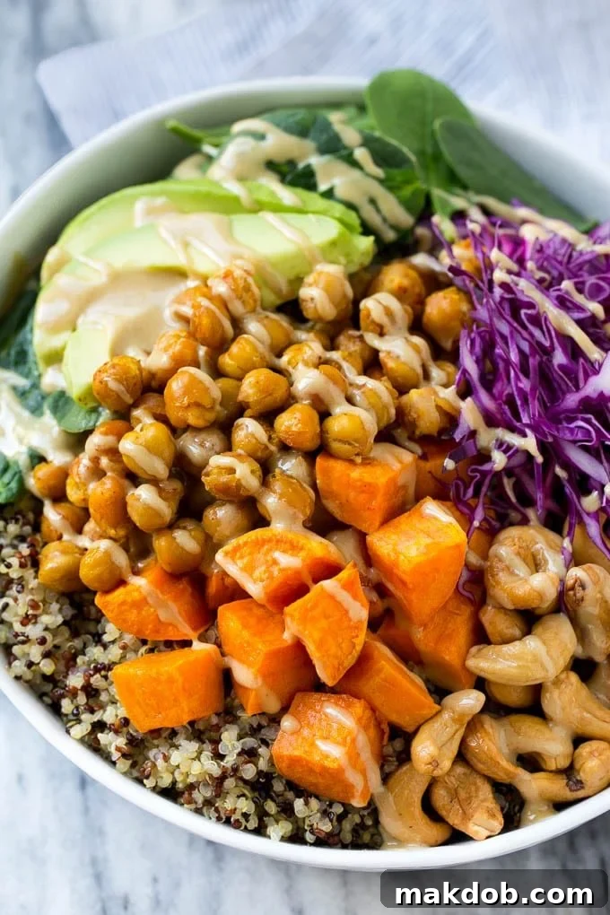 A Buddha bowl filled with quinoa, sweet potatoes, chickpeas and avocado, then drizzled with tahini dressing.